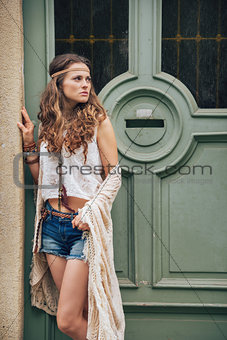 Young trendy hipster woman standing outdoors against wooden door