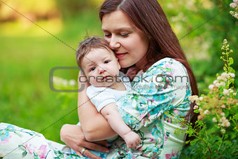 Mother kisses baby son, close-up, summer