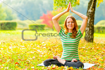 girl in a striped T-shirt in autumn park doing exercises