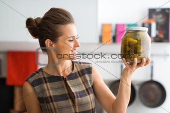 Closeup of woman holding up big jar of freshly-made dill pickles