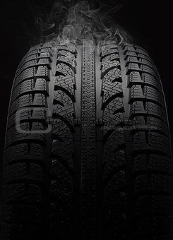 Close-up of car tire with smoke over black background