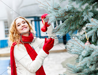 Woman decorating Christmas tree outside