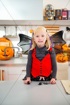 Interested girl in halloween bat costume in kitchen