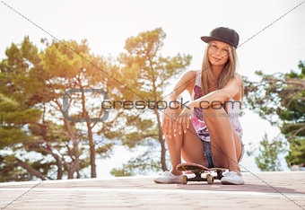 Young woman sitting on a skateboard outdoors