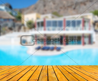 Wood table in perspective. Blurred hotel with pool and mountains view