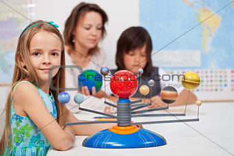 Kids study the solar system under their teacher supervision