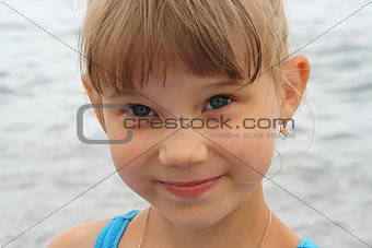 smiling blue-eyed baby girl on sea background