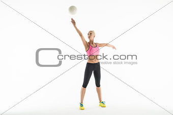 Rhythmic gymnast doing exercise with ball in studio.