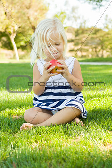 Little Girl Sitting and Eating Apple Outside