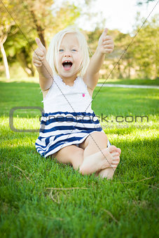 Cute Little Girl with Thumbs Up in the Grass
