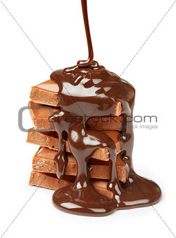 chocolate syrup being poured onto chocolate pieces isolated