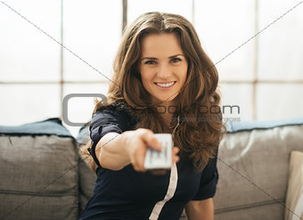 Happy woman sitting on sofa and watching tv in loft apartment