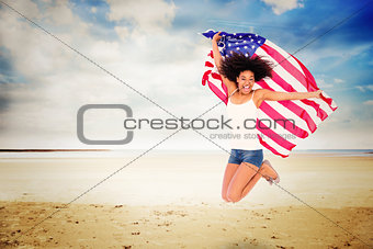 Composite image of pretty girl wrapped in american flag jumping and smiling at camera