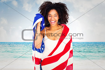Composite image of pretty girl wrapped in american flag smiling at camera