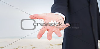 Composite image of mid section of a businessman with hands on a table