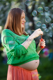 Pregnant woman blowing bubbles outdoor