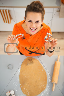 Woman holding cookie cutters for Halloween biscuits in kitchen