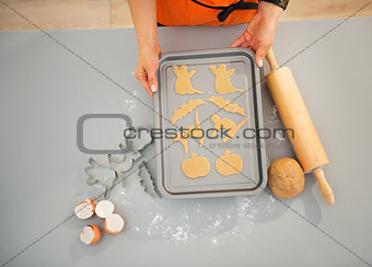 Closeup on housewife with tray of uncooked Halloween biscuits