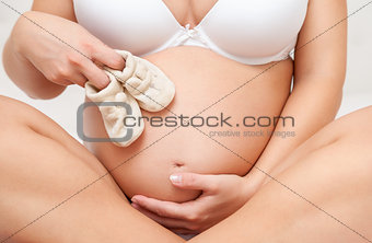 Pregnant woman holding a pair of tiny shoes