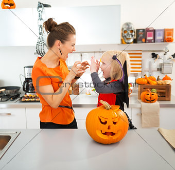 Halloween dressed girl with young mother scaring each other