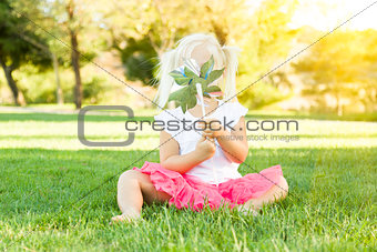 Little Girl In Grass Blowing On Pinwheel