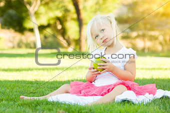 Little Girl In Grass Eating Healthy Apple