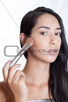 Beautiful girl with makeup brush on her face