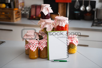 Glass jars of preserved vegetables with notebook and pen
