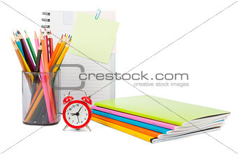 Crayons with notebooks and alarm clock