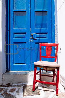 Detail of colorful blue door and red wooden chair