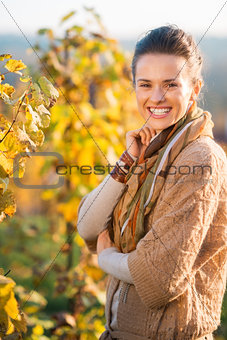 Smiling woman winegrower standing in vineyard outdoors in autumn