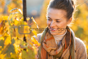 Woman winegrower inspecting vines in vineyard outdoors in autumn
