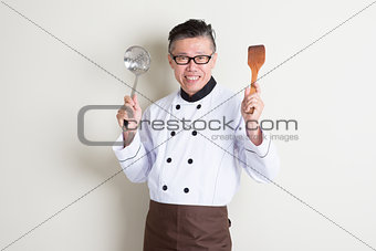 Mature Asian Chinese chef with kitchen tools