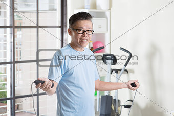 Mature Asian man doing rope skipping exercise