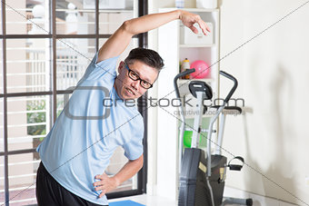 Mature Asian man arms stretching at gym