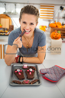 Housewife eating freshly homemade Halloween biscuits in kitchen