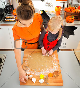 Girl in bat costume with mother making Halloween biscuits