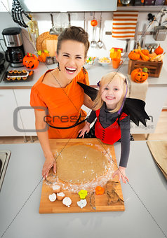 Mother with daughter in bat costume making Halloween cookies