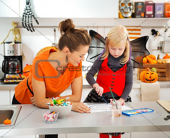 Halloween dressed girl and mother drawing Jack-O-Lantern