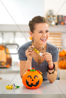 Woman eating trick or treat candy in halloween decorated kitchen
