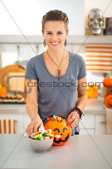 Smiling woman preparing halloween trick or treat candy for kids