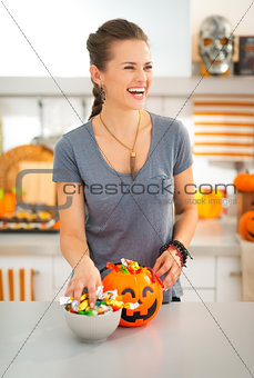 Laughing woman preparing halloween trick or treat candy for kids