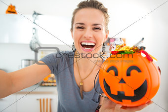 Happy woman making selfie with halloween bucket full of candy