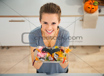 Woman showing dish with trick or treat candy for halloween party