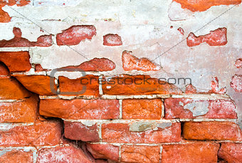 Brick wall with cracks and an old plaster as background