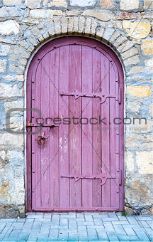 Ancient wooden door in old stone wall.