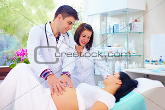 doctor palpates the abdomen of pregnant woman before childbirth