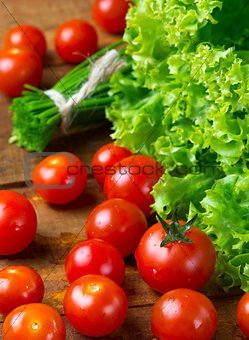 tomatoes and green vegetables on wooden dark background