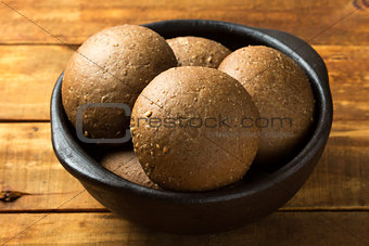 Rye bread in dark clay bowl on wooden background
