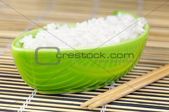 Rice in green clay bowl with wooden chopsticks